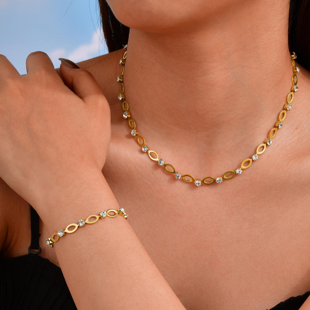 Gold necklace and bracelet set on a person against a blue sky background