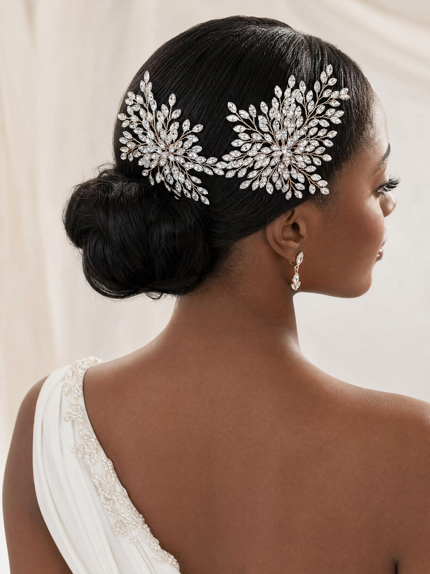 Woman with intricate hairpiece and earrings against a neutral background